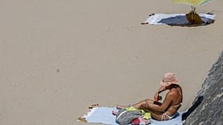 Une femme utilise de la crème solaire lundi 30 juin 2025 sur la plage d'Hendaye, dans le sud-ouest de la France.