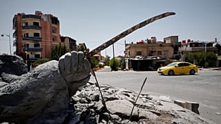 A car drives by a destroyed statue following last week's sectarian clashes in the Druze-majority town of Suwayda, 25 July 2025,