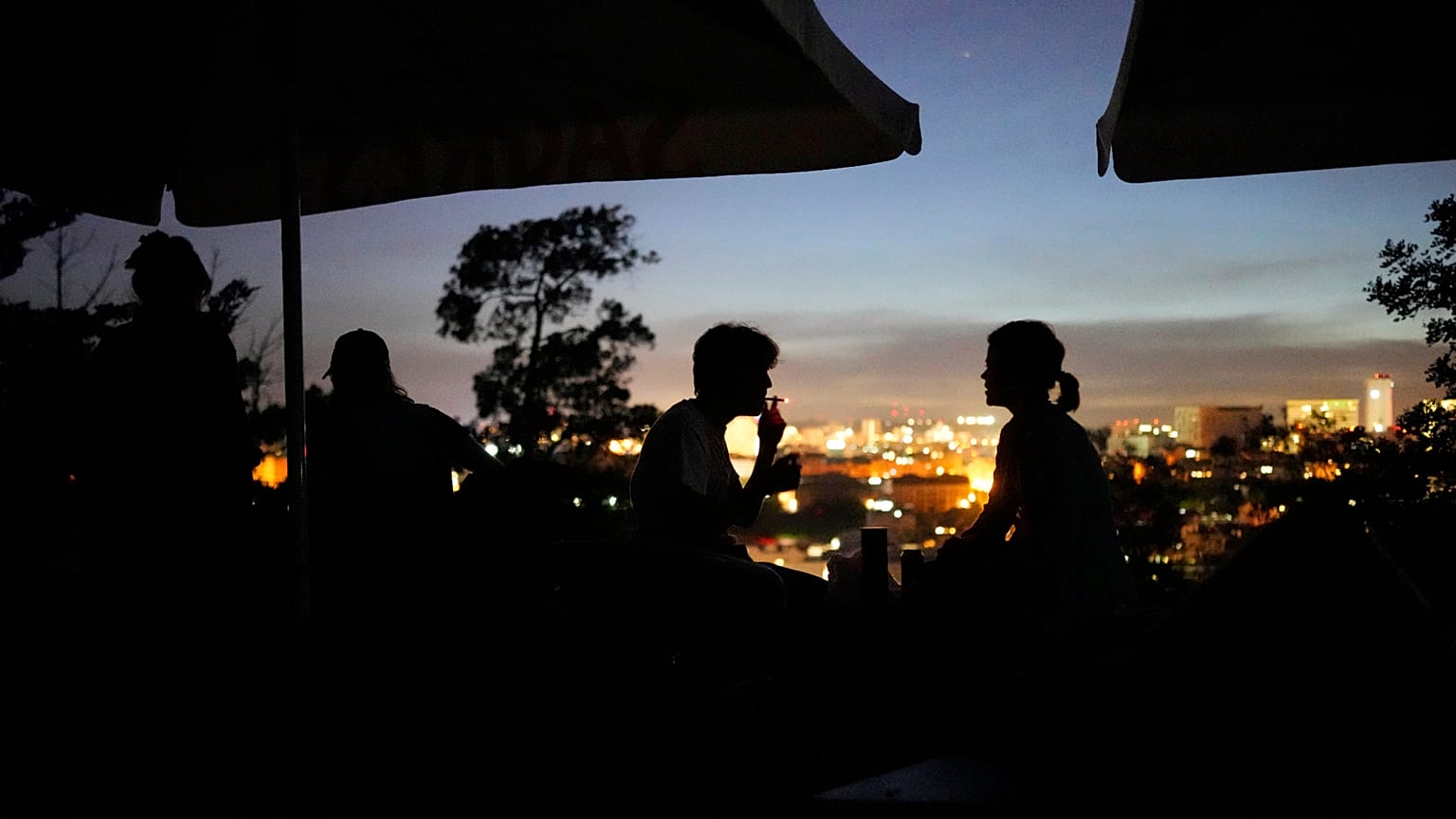 ARQUIVO - Pessoas sentadas no terraço de um bar fechado no miradouro do Monte Agudo, com vista para Lisboa, durante uma falha de energia em todo o país, 28 de abril