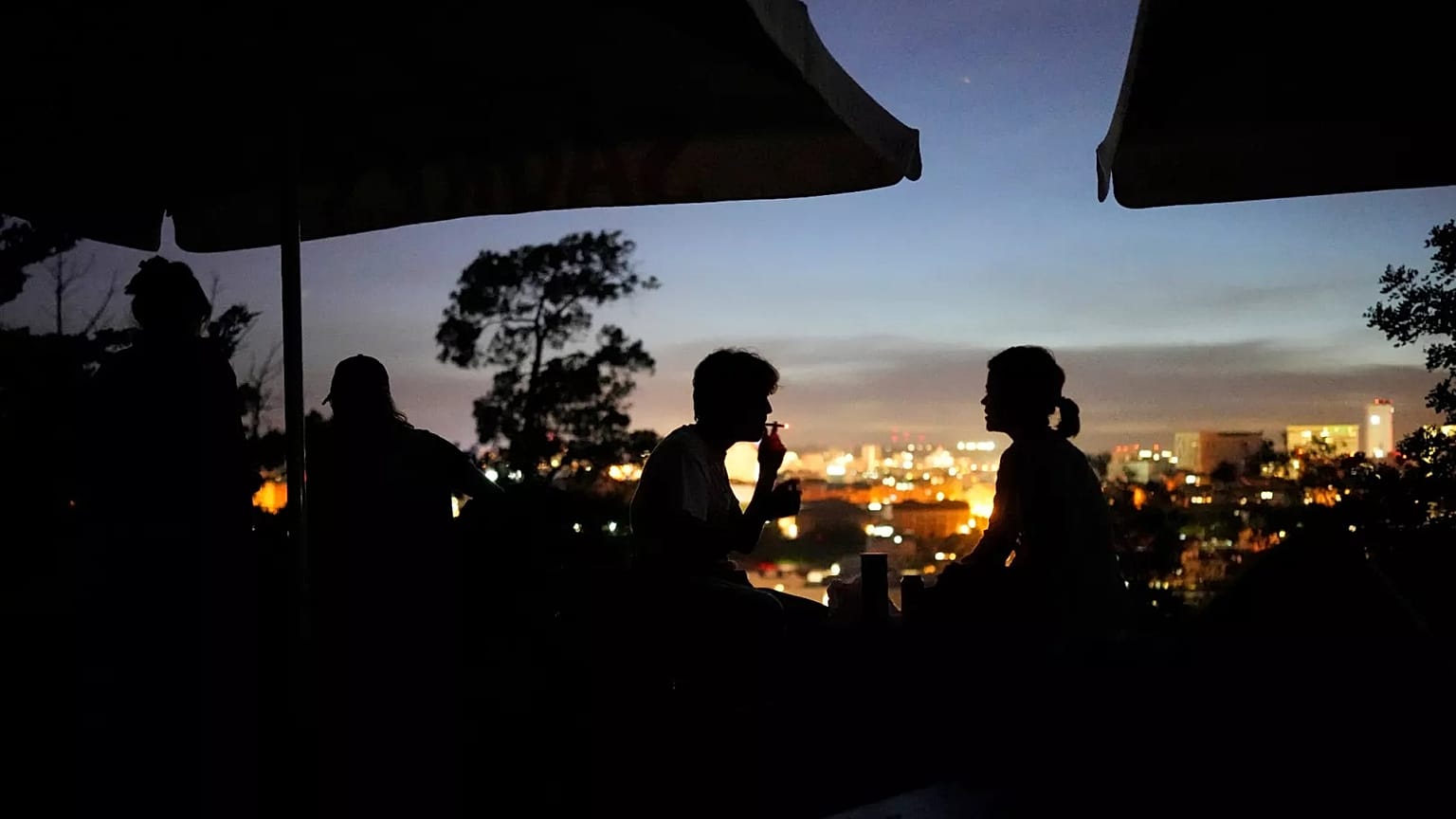 People sit on the terrace of a closed bar at the Monte Agudo viewpoint overlooking Lisbon during a nationwide power outage, 28 April, 2025