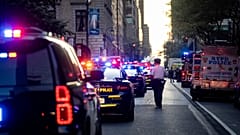 Bir New York polis memuru, 28 Temmuz 2025 Pazartesi günü New York'ta, Manhattan'da insanların vurulduğu ofis binasının dışındaki 52. Cadde üzerinde nöbet tutuyor.