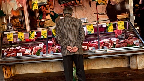 A man buys meat at a market in Barcelona, Spain, Wednesday, March 28, 2012.