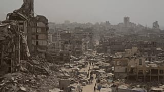 People walk along a street lined with destroyed buildings following Israeli bombardments during the Israel-Hamas war in the Gaza Strip, 29 July, 2025
