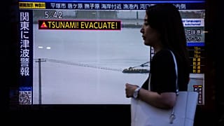 Um peão passa por um ecrã de televisão que mostra um aviso de tsunami em Tóquio, quarta-feira, 30 de julho de 2025.