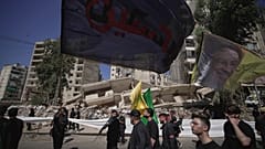أنصار حزب الله يسيرون أمام مبنى دمرته غارة جوية إسرائيلية في الضاحية الجنوبية لبيروت، لبنان، الأحد 6 يوليو/تموز 2025.