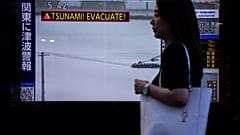 Un piéton passe devant un écran de télévision affichant une alerte au tsunami à Tokyo, mercredi 30 juillet 2025.