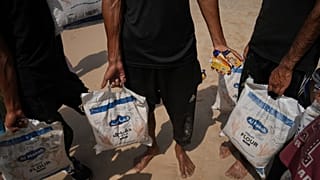 فلسطينيون يجمعون المساعدات التي هبطت في البحر الأبيض المتوسط بعد إسقاطها جواً فوق وسط غزة