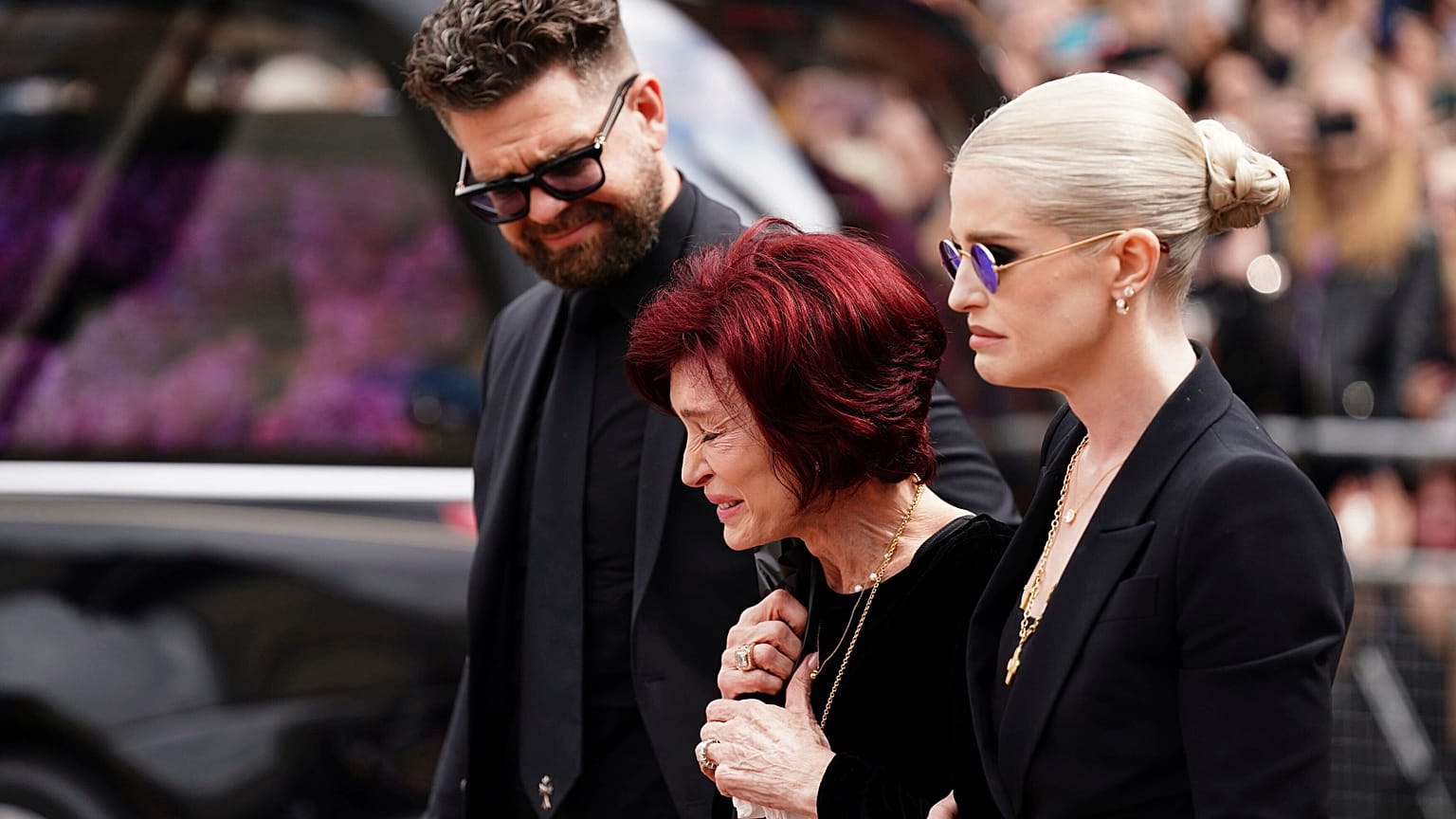 La famille d'Ozzy Osbourne admire les fleurs et observe celles déposées sur le banc du Black Sabbath Bridge à Birmingham, en Angleterre, mercredi 30 juillet 2025