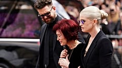 Die Familie von Ozzy Osbourne legt Blumen nieder und betrachtet die Blumen, die am Mittwoch, den 30. Juli 2025, auf der Bank der Black Sabbath Bridge in Birmingham, England, hinterlassen wurden.