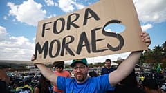 A supporter of Brazil's former President Jair Bolsonaro holds a sign "Moraes get out" in during a protest over Bolsonaro's Supreme Court trial in Brasília, 29 July 2025