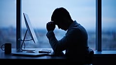 Un hombre se sienta solo frente al ordenador de su trabajo.