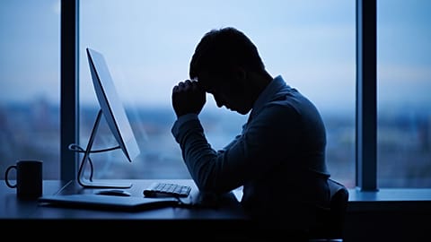 A man sits alone at his work computer.
