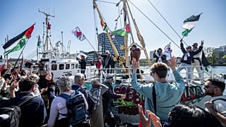 متظاهرون يحملون أعلامًا فلسطينية على رصيف الميناء، بينما كانت سفينة "حنظلة" المتجهة إلى غزة ترسو على جسر السفن البخارية في ميناء مالمو، السويد، الأربعاء 8 مايو/أيار 2024.