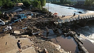 Pessoas atravessam uma margem de rio danificada após uma inundação repentina no distrito de Jizhou, em Tianjin, a 29 de julho de 2025