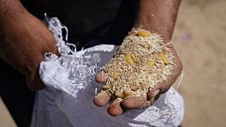 رجل فلسطيني يعرض محتويات طرود المساعدات الإنسانية بعد إسقاطها جواً على الزوايدة، في وسط قطاع غزة، الأربعاء 30 يوليو/تموز 2025.