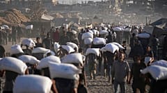 فلسطينيون يحملون أكياس الدقيق التي تم تفريغها من قافلة مساعدات إنسانية في طريقها إلى مدينة غزة من شمال قطاع غزة