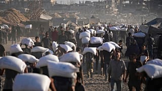 فلسطينيون يحملون أكياس الدقيق التي تم تفريغها من قافلة مساعدات إنسانية في طريقها إلى مدينة غزة من شمال قطاع غزة