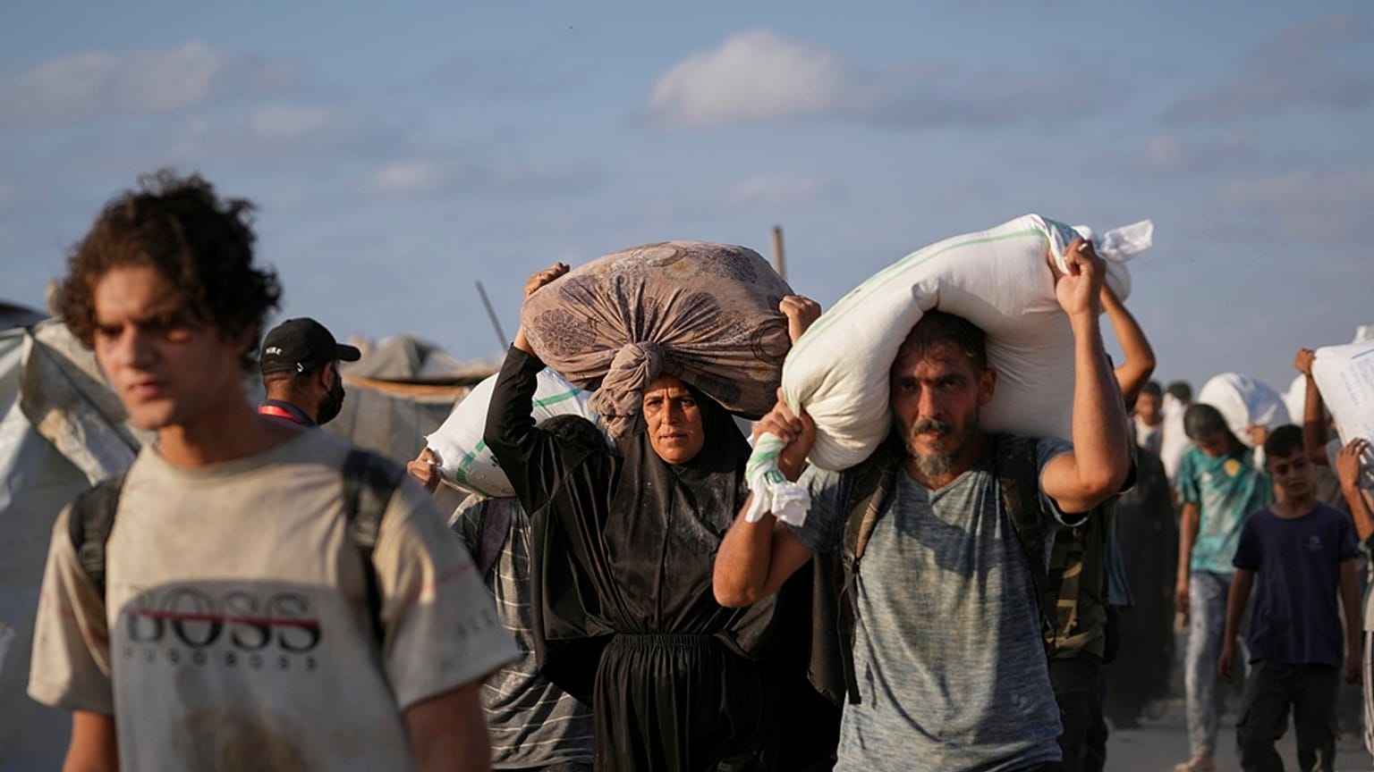 يحمل فلسطينيون أكياس دقيق أُنزلت من قافلة مساعدات إنسانية متجهة إلى مدينة غزة من شمال قطاع غزة، يوم الخميس 31 يوليو/تموز 2025. 