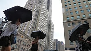 Peões usam guarda-chuvas enquanto passam pelo Empire State Building durante uma tempestade na quinta-feira, 31 de julho de 2025, em Nova Iorque