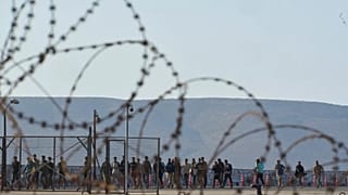 Migrantes resgatados a sul de Creta caminham após a sua chegada ao porto de Lavrio, 10 de julho de 2025