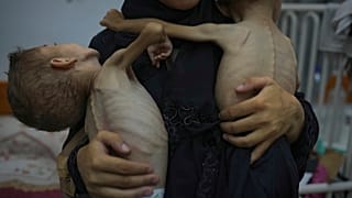 أم تحمل طفليها اللذان يعانيان من سوء التغذية واضطراب في الأعصاب الوراثية غزة 29 يوليو 2025
