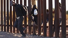 Illegális bevándorlók jutnak be az Egyesült Államokba a mexikói határkerítésen levő résen át az arizonai Lukeville településnél 2023. december 12-én