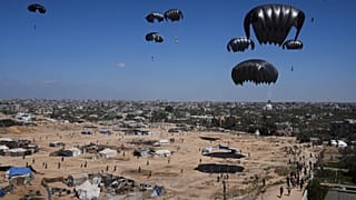 Palestinianos apressam-se a recolher ajuda humanitária lançada por via aérea em Zawaida, no centro da Faixa de Gaza, quinta-feira, 31 de julho de 2025.