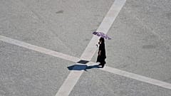 Archivo (02.08.2025): Una mujer utiliza un paraguas para protegerse del sol mientras cruza la Praça do Comércio, en Lisboa, en un día caluroso