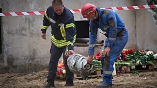 DATEI: Suchende tragen ein Fragment der russischen Rakete, die am Donnerstagabend in ein mehrstöckiges Wohnhaus einschlug, in Kiew, 1. August 2025