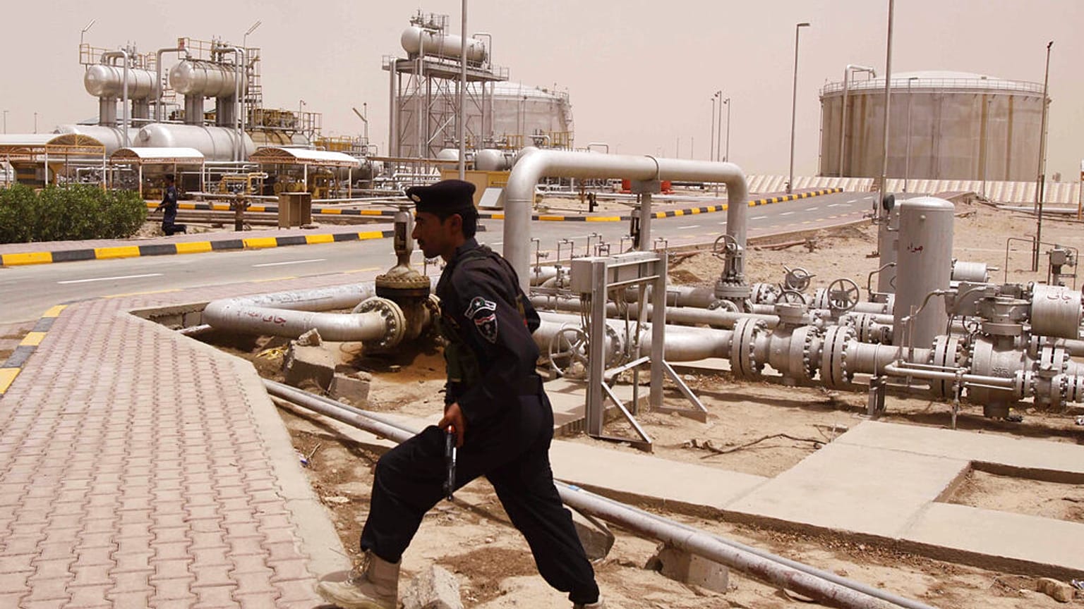 شرطي عراقي يوفر الأمن في مصفاة الشعيبة النفطية وخط الأنابيب قرب مدينة البصرة يوم الثلاثاء، 30 يونيو/حزيران 2009.