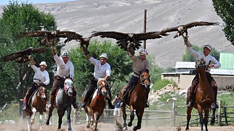 Kyrgyz hunters ride horses with their golden eagles during the Traditional Eagle Hunting Salbuurun Festival on the southern shore of Issyk-Kul lake