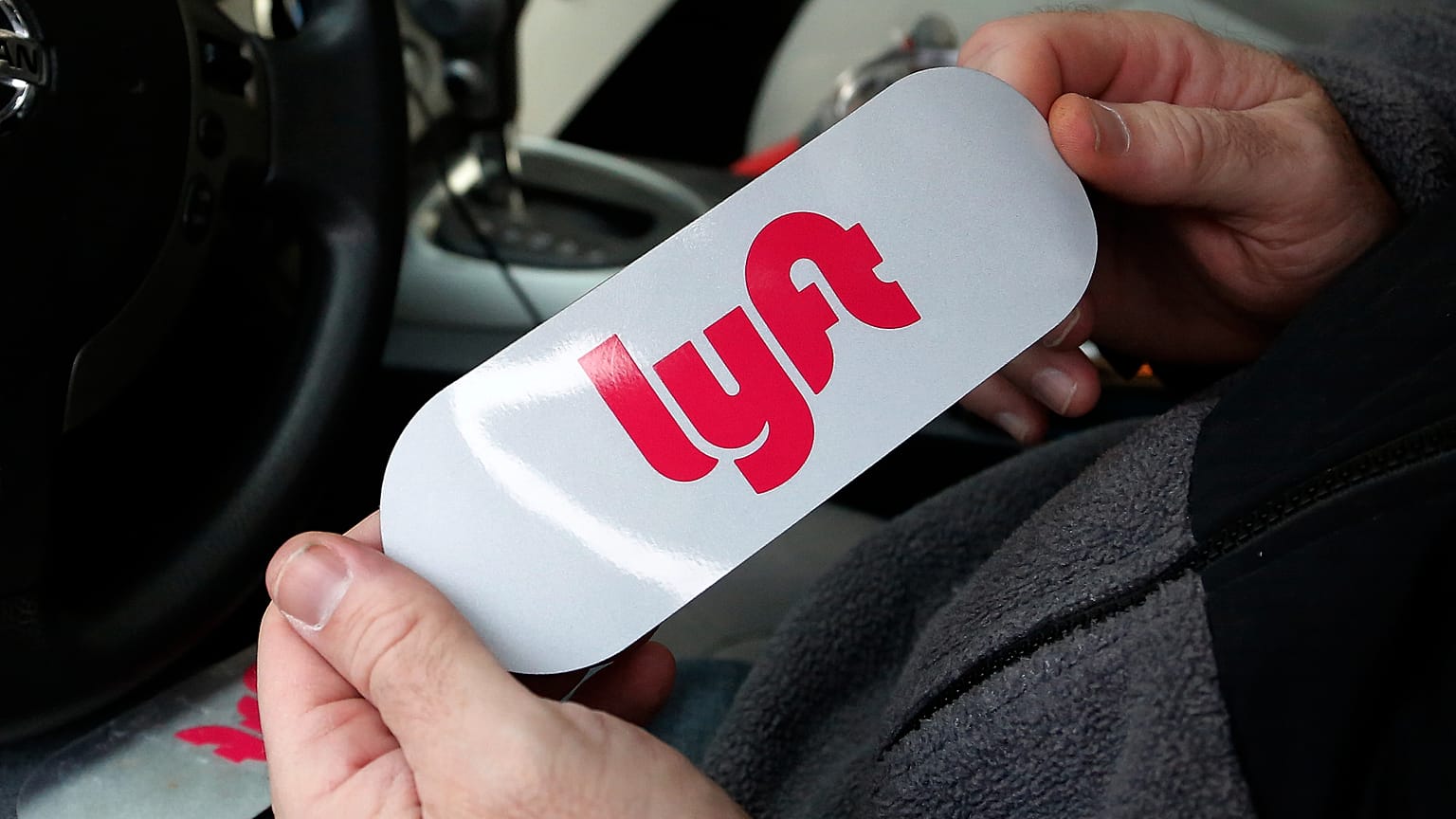In questa foto del 31 gennaio 2018, un autista di Lyft tiene in mano un logo Lyft prima di installarlo sulla sua auto a Pittsburgh.