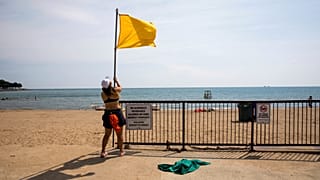 Una socorrista iza la bandera amarilla en una playa de Estados Unidos.
