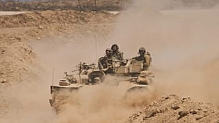 Israeli soldiers drive on their armoured personnel carrier back from inside the northern Gaza Strip into southern Israel, 29 July, 2025