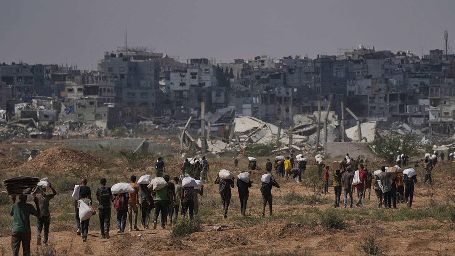 Imagen de palestinos llevando sacos con alimento en Gaza.
