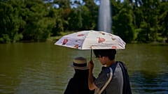 Ein Paar schützt sich bei warmem Wetter mit einem Regenschirm im Retiro Park in Madrid, Spanien, Montag, 4. August 2025.