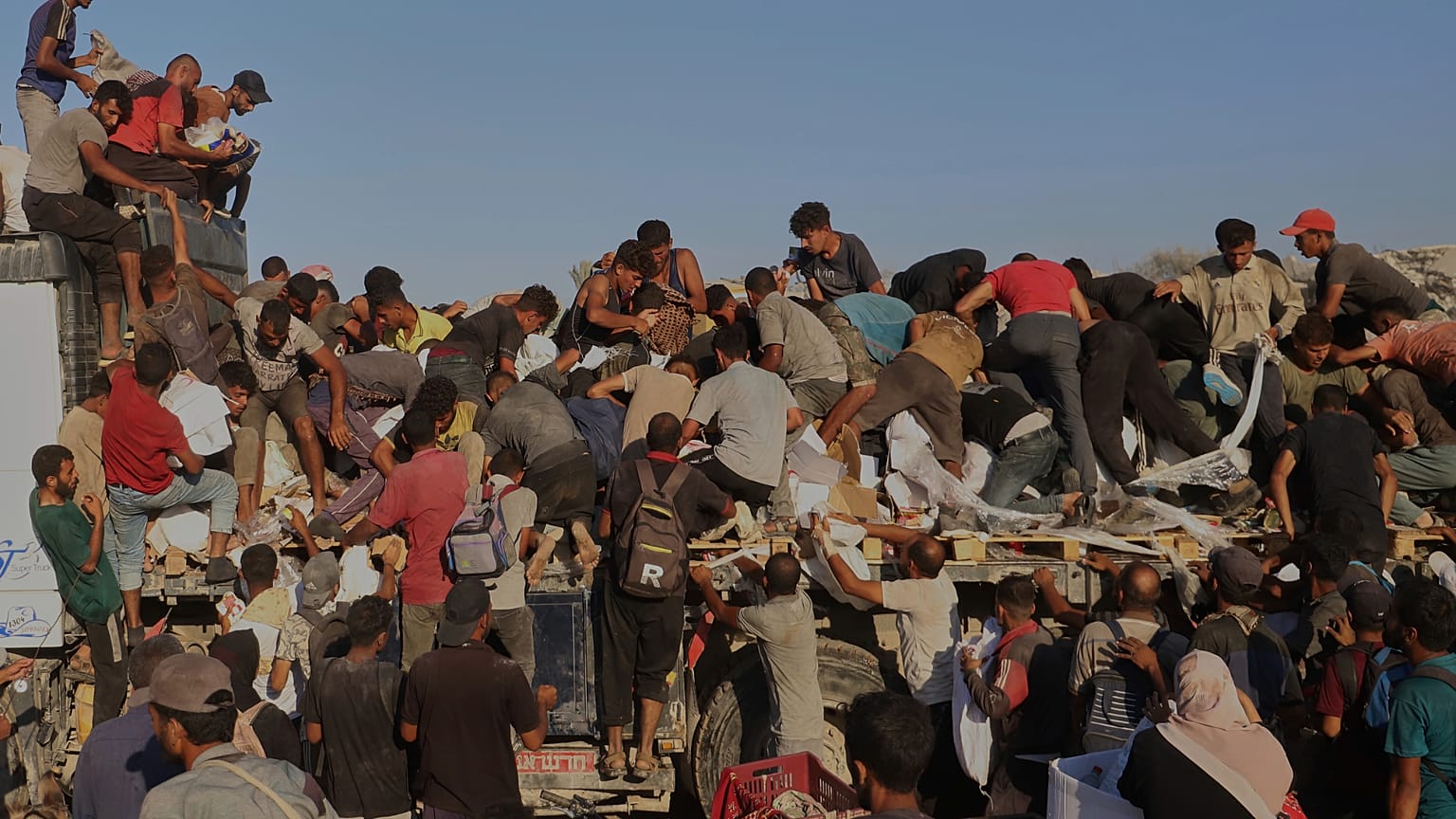 Os palestinianos lutam para obter alimentos e ajuda da parte de trás de um camião que se desloca ao longo do corredor de Morag, perto de Rafah, no sul da Faixa de Gaza, segunda-feira, 4 de agosto de 2025. 