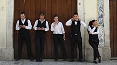 El camarero Joao Sintra, segundo a la derecha, se ajusta la corbata mientras la camarera Maria Almas, en el centro, fuma un cigarrillo durante un descanso con sus compañeros de trabajo en el centro de Lisboa. 27 de abril de 2013.