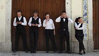 Kelner Joao Sintra, drugi z prawej, poprawia krawat, gdy kelnerka Maria Almas, w środku, pali papierosa podczas przerwy ze współpracownikami w centrum Lizbony. 27 kwietnia 2013 r.