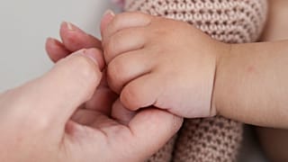 Un parent tient la main de son bébé.
