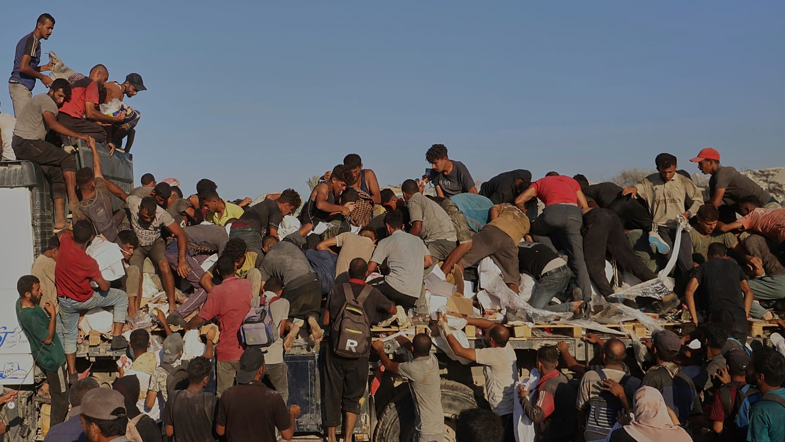 Filistinliler, Gazze Şeridi'nin güneyindeki Refah yakınlarındaki Morag koridorunda hareket eden bir kamyonun arkasından yiyecek ve insani yardım almak için mücadele ediyor, 4 Ağustos 2025