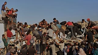 Los palestinos luchan por conseguir comida y ayuda humanitaria desde la parte trasera de un camión mientras se mueve por el corredor de Morag cerca de Rafah, en el sur de la Franja de Gaza, el 4 de agosto de 2025