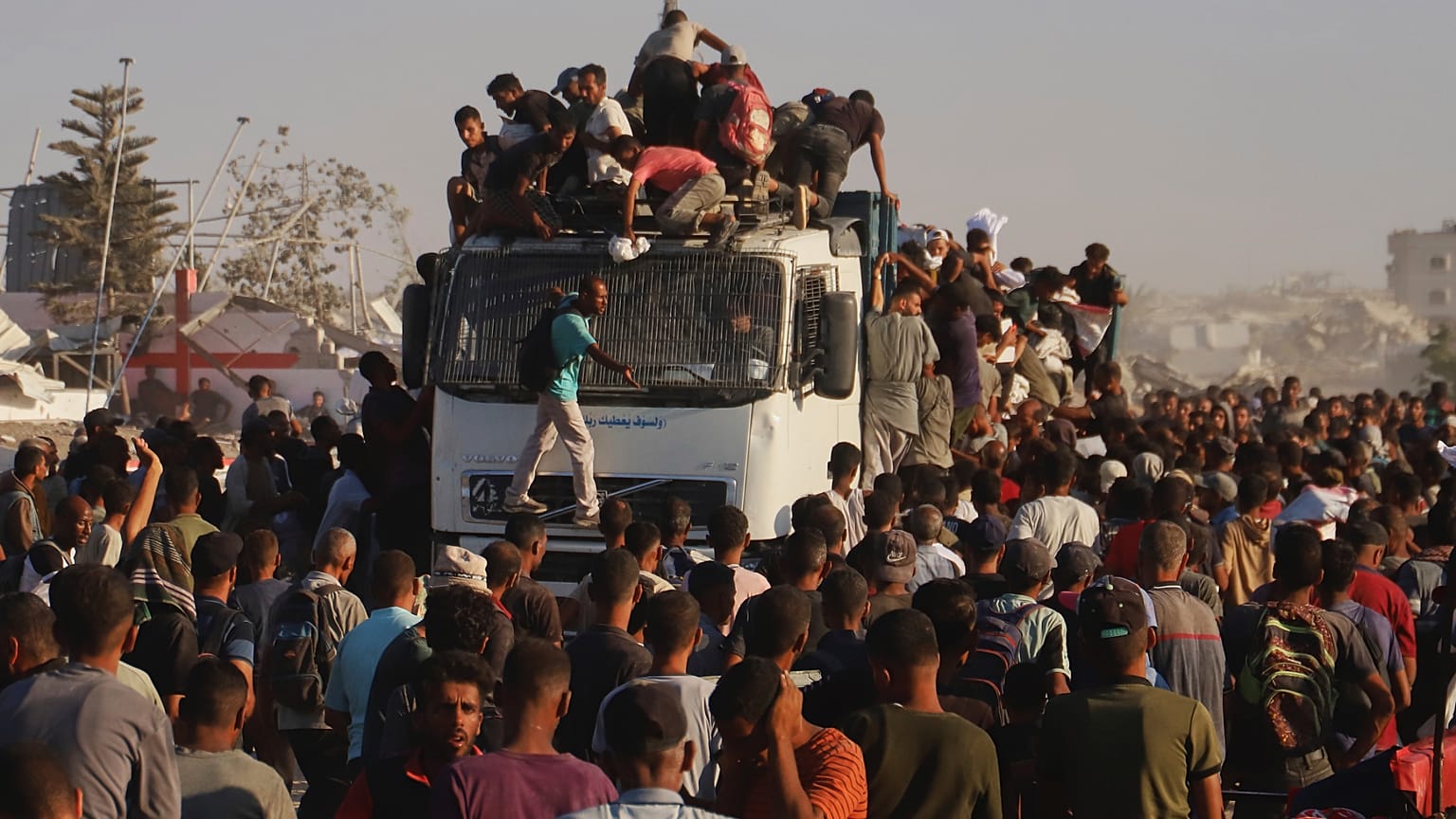 فلسطينيون يركبون شاحنة محملة بالغذاء والمساعدات الإنسانية أثناء تحركها على طول ممر موراغ بالقرب من رفح، جنوب قطاع غزة، الاثنين 4 أغسطس/ آب 2025.