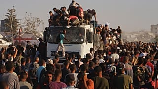 فلسطينيون يركبون شاحنة محملة بالغذاء والمساعدات الإنسانية أثناء تحركها على طول ممر موراغ بالقرب من رفح، جنوب قطاع غزة، الاثنين 4 أغسطس/ آب 2025.