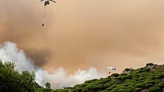 Helicópteros de combate a incêndios lançam água para extinguir um incêndio em Torre de la Peña, no sul de Espanha, terça-feira, 5 de agosto de 2025.
