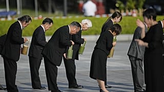 Os convidados oferecem água durante uma cerimónia comemorativa do 80.º aniversário do bombardeamento no Parque Memorial da Paz de Hiroshima, em Hiroshima, no oeste do Japão, quarta-feira, 6 de agosto de 2025.