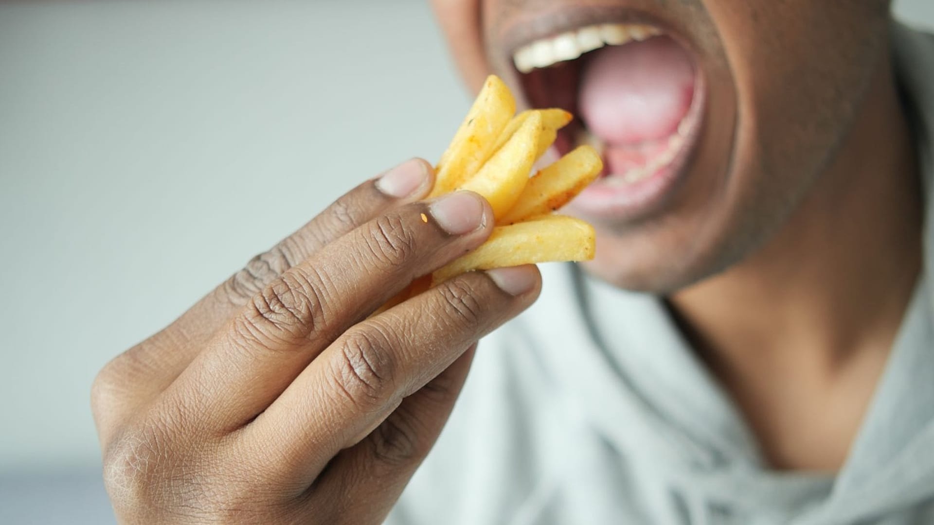 Мужчина ест картофель фри.