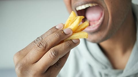 A man eats French fries.