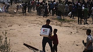 Filistinliler, Birleşik Arap Emirlikleri'nden gelen insani yardım paketlerini Gazze Şeridi'nin orta kesimindeki Deir Al-Balah'a havadan indirildikten sonra topluyor.