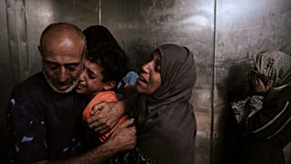 Filistinliler, 6 Ağustos 2025'te Gazze Şehri'ndeki Şifa Hastanesi'nde, Zikim geçişinden Gazze Şeridi'ne giren yardım kamyonlarına ulaşmaya çalışırken öldürülen akrabalarına yas tutuyor.